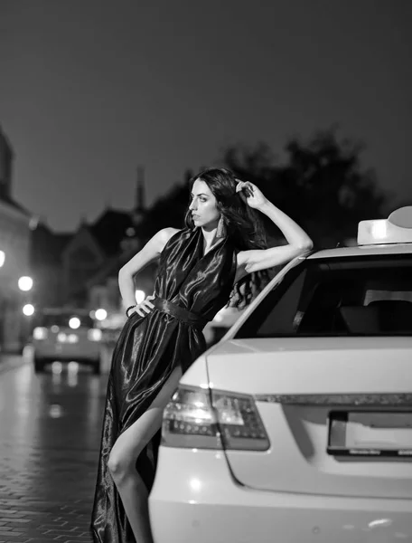 Ночной город с принцессой в стиле знаменитости. Роскошная женщина в вечернем платье в ночном городе едет на бал на такси. Девушка с гламурным макияжем. Мода и красота деловой леди. Сексуальная девушка в элегантном платье — стоковое фото