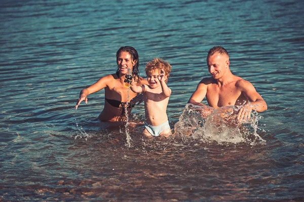 Αγάπη και εμπιστοσύνη ως οικογενειακές αξίες. αγάπη ευτυχής οικογένεια παίζει στο νερό της θάλασσας στο ηλιοβασίλεμα. — Φωτογραφία Αρχείου