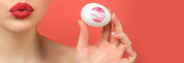 Egg hunt. Red lip imprint on easter egg on red background. Lipstick kiss print. Female mouth.