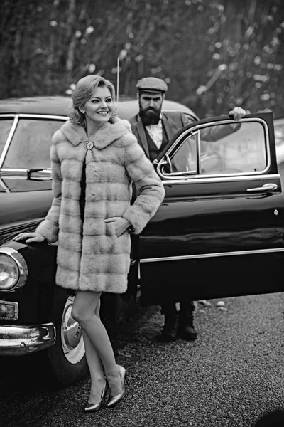 Retro collectie auto en auto repareren door monteur bestuurder. Bebaarde man en sexy vrouw in bontjas. Escort meisje door de beveiliging. Paar verliefd op romantische datum. Reis- en zakelijke reis of hitch hiking. — Stockfoto