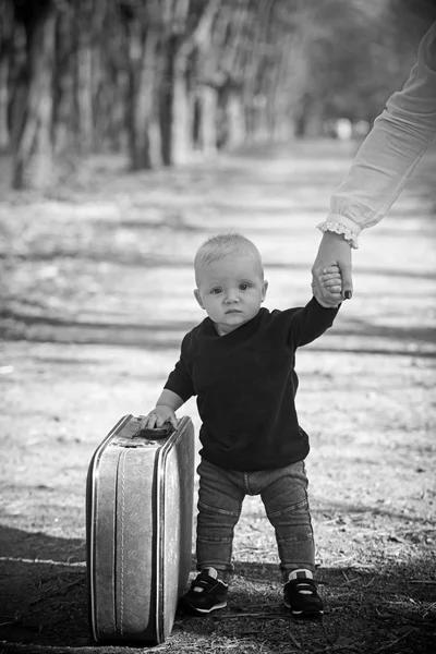 Детский путешественник носит винтажную сумку с маминой рукой, детством. Детские путешествия с ретро чемоданом на природный ландшафт — стоковое фото