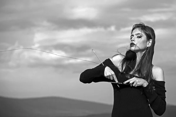 Knitting, fashion makeup and hairstyle of woman. knitting black dress on young woman on blue sky background, copy space