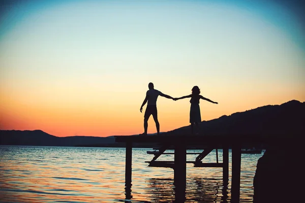 Happy couple dance to sunset sea. Silhouette tropical vacations concept.