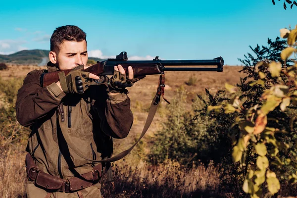 Jäger mit leistungsstarkem Gewehr mit Zielfernrohr, das Tiere beobachtet. Jäger mit Gewehr auf Jagd. Spurensuche. — Stockfoto