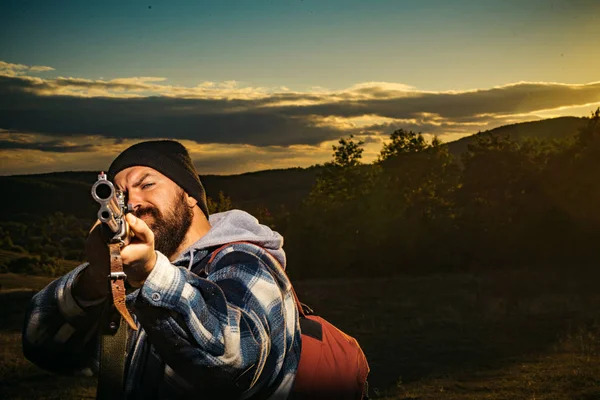 Hunter s brokovnicí zbraní na lov. Lovecké náčiní - lovecké potřeby a vybavení. Vousatý lovec muž drží zbraň a procházky v lese. — Stock fotografie