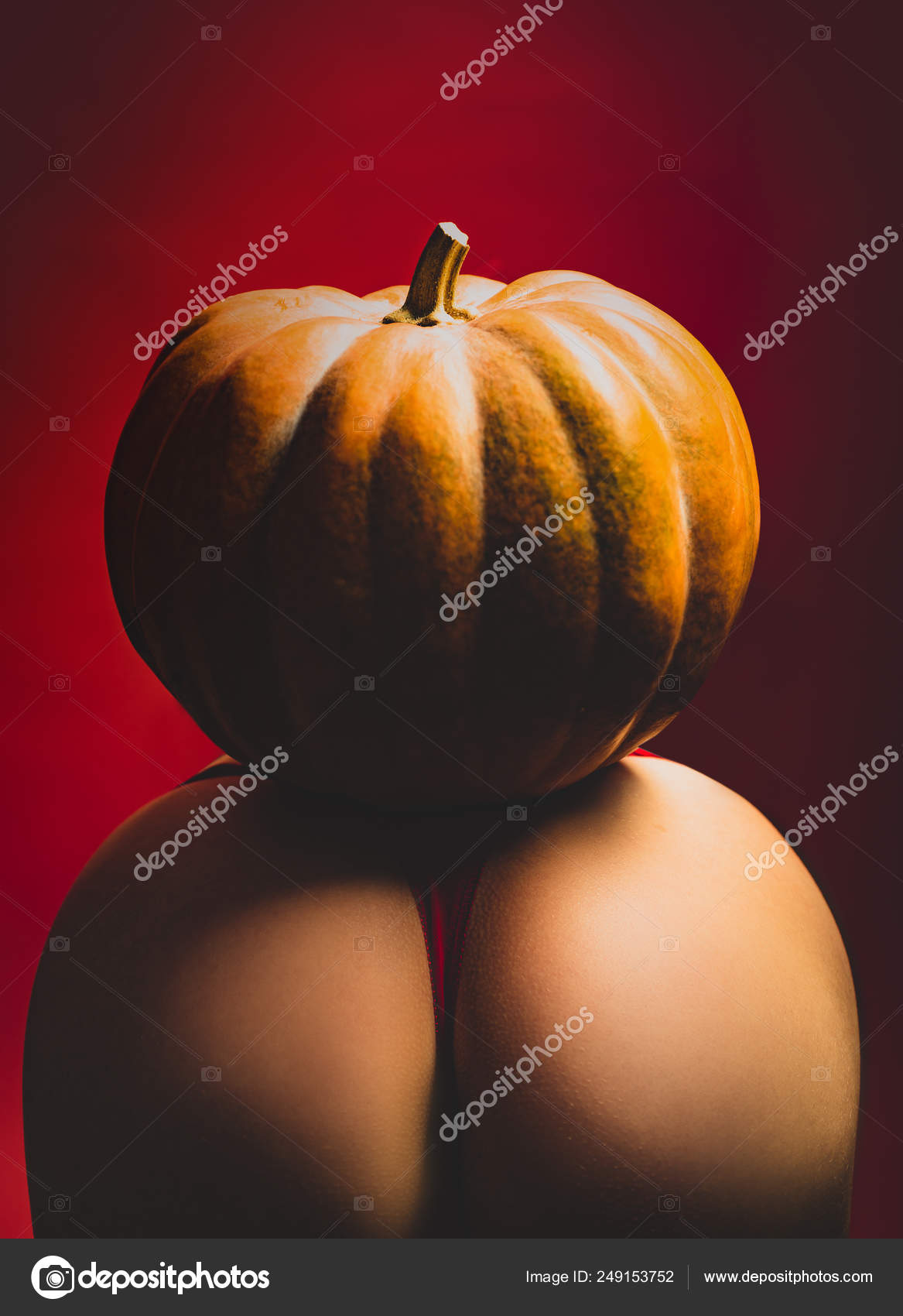Pumpkins on big ass. Female sensual ass posing with red panties and pumpkin. Halloween festival decorations. Sex costume for celebrates Halloween photo
