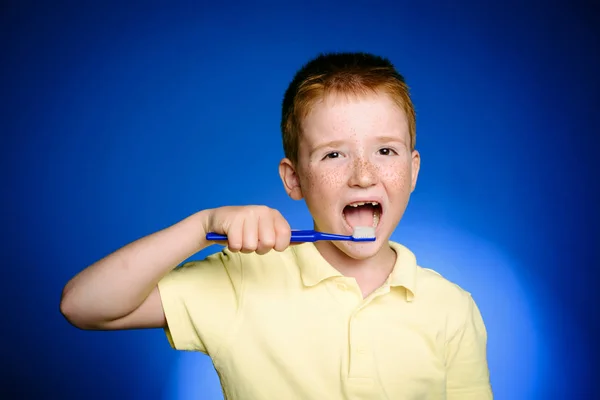 Smiling little boy child with toothbrush in hand isolated on blue background. Child Health care, child dental hygiene. Little boy with tooth brush. Shirt design, health, oral hygiene. — Stock Photo, Image