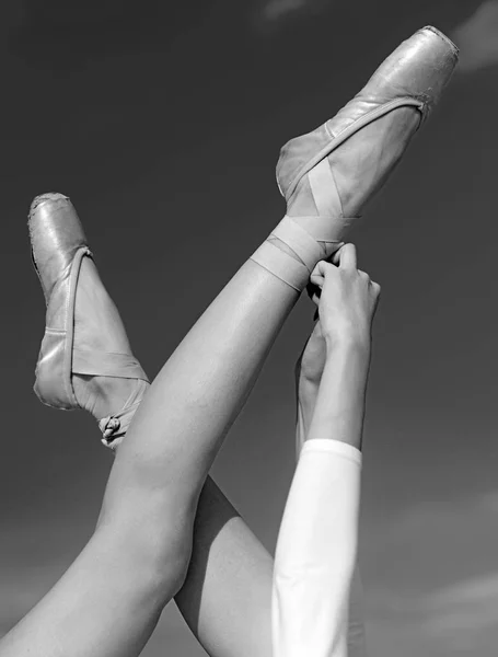 Touching the sky. Pointe shoes worn by ballet dancer. Ballet slippers. Ballerina shoes. Ballerina legs in ballet shoes. Female feet in pointe shoes. Classic dance style. Concert dance performance