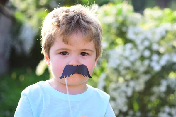 Little boy child in green forest. Childhood happiness. Childrens day. spring holiday. Sunny weather. Small child with summer party moustache. Happy kid in blooming nature. Hello summer