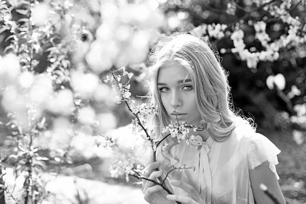 Krásná blondýnka v kvetoucí šeřík zahrady, přírodní pozadí. Mladá žena si květiny v zahradě, rozostření. Jarní květ koncept. Lady procházky v parku na slunečný jarní den. — Stock fotografie