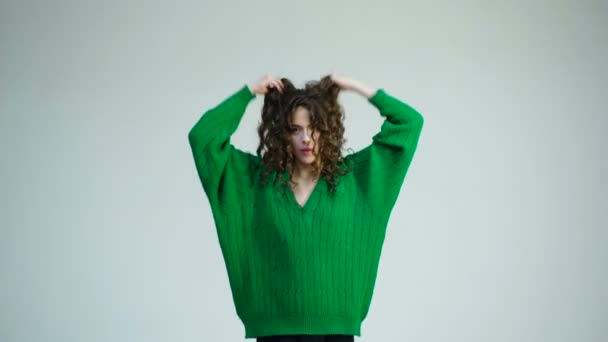 Chica con el pelo rizado en la peluquería en la pared blanca. Aspecto de moda y concepto de belleza. Chica retro con maquillaje elegante y cabello en París. Mujer de moda en jersey verde. Chica parisina en ropa de invierno . — Vídeo de stock