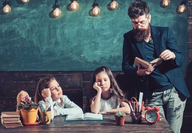 Öğretmen kız öğrenciler için kitap okuyun. Okul çocukları için öğretmen dinle