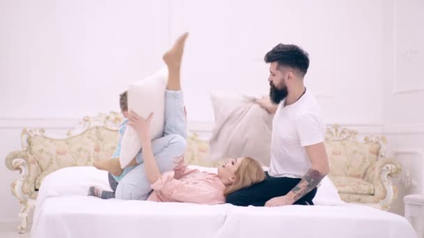 Familia teniendo divertida pelea de almohadas en la cama. Los padres pasan tiempo libre con su hijo. Familia feliz se divierte en el dormitorio mientras la batalla de almohadas. Disfrutando estar juntos. Familia feliz en el dormitorio . — Vídeo de stock