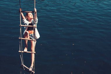 Onun hırs çok uzakta. Güzel kadın üstüne jacobs merdiveni tırmanmak. Şehvetli kadın su yüzey üzerinde ipe asmak. Seksi kadın halat merdivene tırmanma. Ona çok yüksek hırs, kopya alanı elde