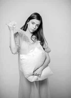 Bayan şeffaf mavi geceliği ve beyaz iç çamaşırı tutan bıçak ve yastık, gri arka plan. Uzun saçlı kadın ihale Pijama giyiyor. Kız sakin yüzünde yastık keser. Hassasiyet ve zulüm kavramı.