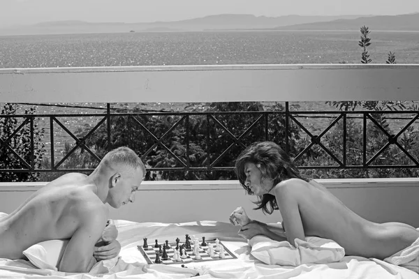 Love relations of couple playing chess on balcony. Couple in love relax on hotel terrace. Family and valentines day. Summer holidays and travel vacation. Sexy woman and man at sea resort — Stock Photo, Image