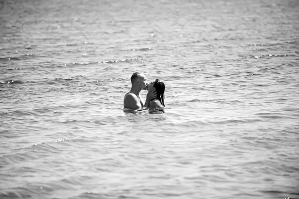 Familia feliz en la playa besándose en el agua . — Foto de Stock