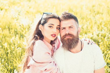Sakal ve kadın oturur bahar günü çimenlerin üzerinde olan adam. Bahar eğlence kavramı. Aşık çift zaman açık havada ve hugs harcamak. Çayır, Doğa arka plan üzerinde oturan mutlu rüya gibi yüzler üzerinde çift.