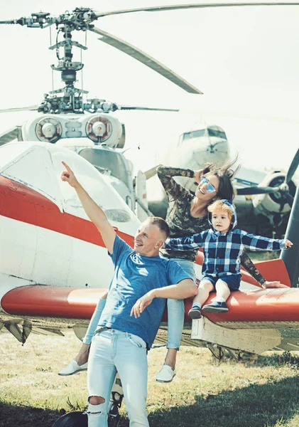 Flight ahead. Helicopter tour and travel. Family vacation. Family couple with child on vacation trip. Mother and father with son at helicopter. Air travel. Enjoying travelling fun. Travelling by air