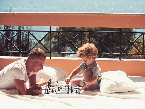 Love and trust as family values. Family travel with kid on fathers day. Summer vacation of happy family. Child play chess with father. father with son on balcony play chess