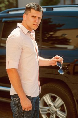 Sürücü hazır yakınındaki şehir sokak araba. Şık giysiler açık güneşli üzerinde iş adamı. Otomobil taşıma adam. Seyahat ve ulaşım kavramı