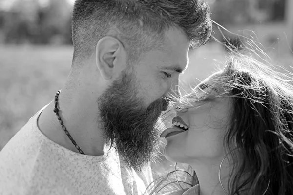 Lady with pink tongue licking bearded macho. Couple kissing outdoors, nature on background, close up. Kiss concept. Couple in love on happy faces relaxing and kissing with tongue.