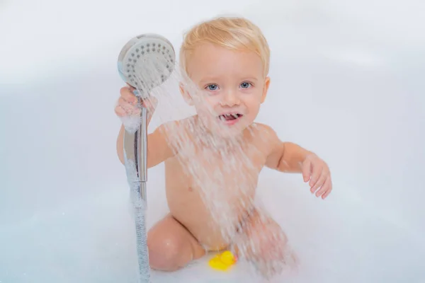 Aranyos szőke totyogó fiú birtoklás móka-val víz által véve fürdő fürdőkád. Bébi bath játék. Fürdő. Boldog gyermekkor. — Stock Fotó