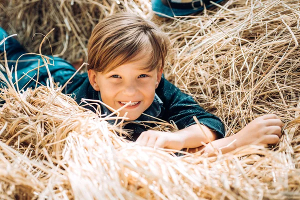 Niño sosteniendo pan de oro y yace en el heno. Adiós verano - hola otoño. Venta para toda la colección de otoño, increíbles descuentos y maravillosa elección. Niño en unas vacaciones de otoño en la granja . — Foto de Stock