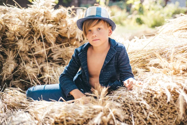 Niño en unas vacaciones de otoño en la granja. Niño sosteniendo pan de oro y yace en el heno. Adiós verano - hola otoño. Venta para toda la colección de otoño, increíbles descuentos y maravillosa opción . — Foto de Stock