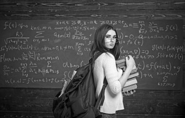 Sınıf kitapları onun elinde büyük kazık ile ortasında genç kadın ayakta. Güzel esmer öğrenci sınavlara tıkınma