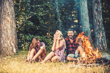 Mutlu arkadaşlar eğlenmeye ormanda piknik. Sakallı adam kız arkadaşı ve kamp ateşi oturan kız kardeşi. Sarışın kız arkadaşı yeme elma ise müzik