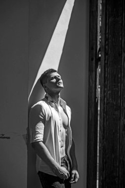 Mavi jeans ve duvara yaslanmış forması giyen adam