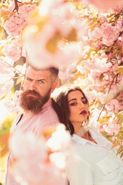 Bahar gününde çiçek açan dalları altında duran kadın ve erkek. Çift sakura ağaçlar duruyor. Aşık çift bahar bahçe, çiçek arka planda, ufuk, yakın kadar vakit. Tarih kavramı.