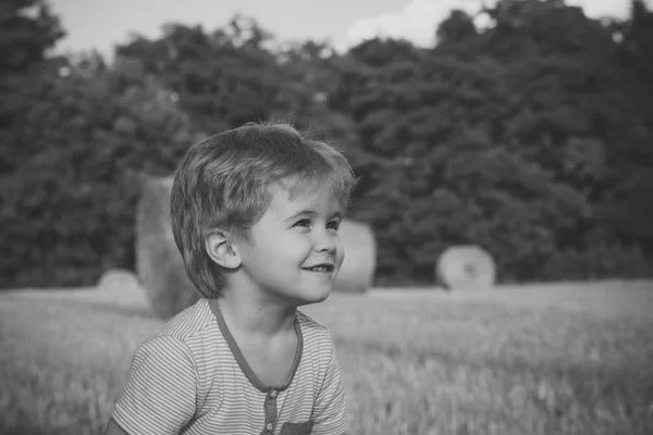 Sonrisa infantil en el campo con fardos de heno, agricultura — Foto de Stock