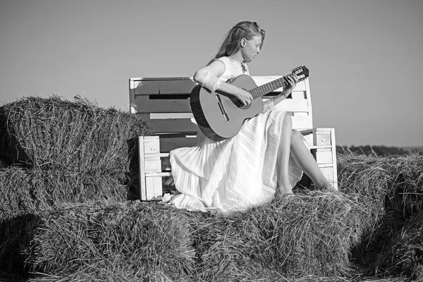 Sensual woman play guitar on wooden bench. Woman guitarist perform music concert. Albino girl hold acoustic guitar, string instrument. Fashion musician in white dress on sunny nature
