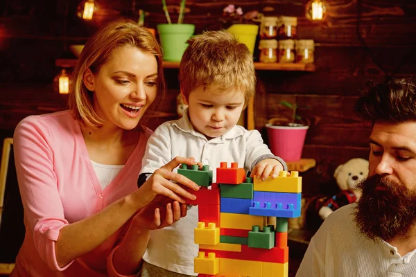 Toy concept. Educational toy for children. Little child play with toy bricks. Son with mother and father build structure with toy construction set