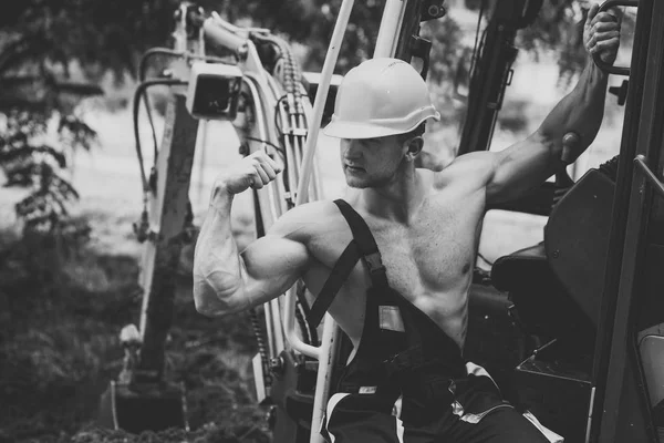 Muscular builder in hard hat shows biceps, poses. — Stock Photo, Image