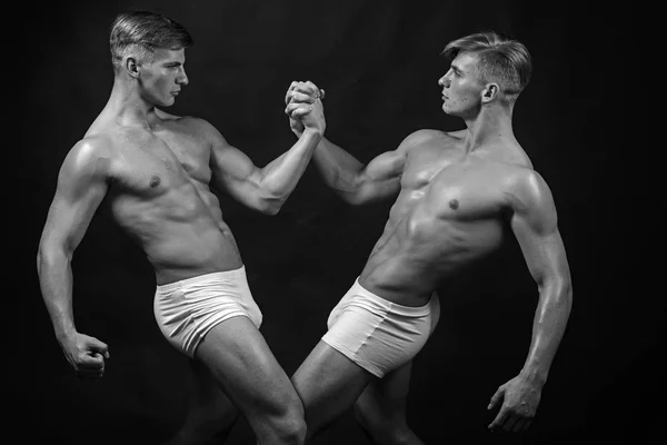 Vänskap av män gör gymnastik. vänskap av tvillingar män med muskulös kropp i bodybuilder utgör. — Stockfoto