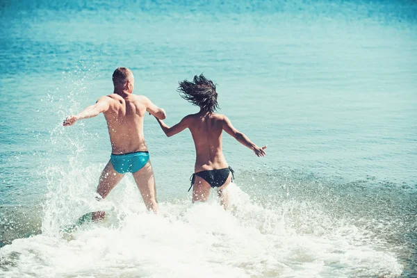 Ευτυχισμένη οικογένεια στην παραλία τρέχει σε θαλασσινό νερό. — Φωτογραφία Αρχείου
