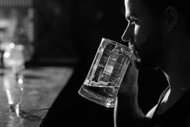 Bir içki ya da iki işten sonra. Bira bardağı ile alkol bağımlısı. Adam alkol barda. Yakışıklı adam içki bira bar sayacı. Bira Restoran. Alkol bağımlılığı ve kötü alışkanlık. Alkollü içecek UOL