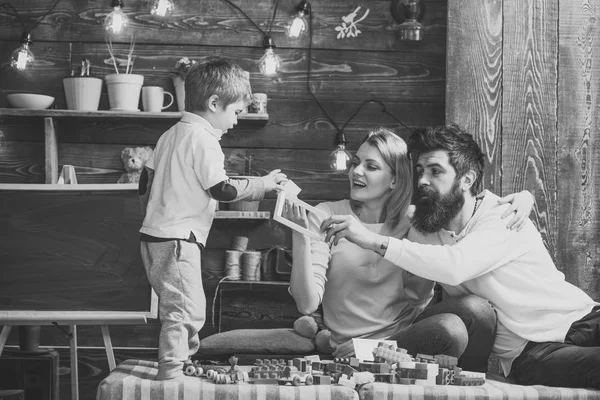 Kid with parents play with plastic blocks, build construction. Father, mother and cute son play with constructor bricks. Caring parents concept. Family on busy face spend time together in playroom. — Stock Photo, Image
