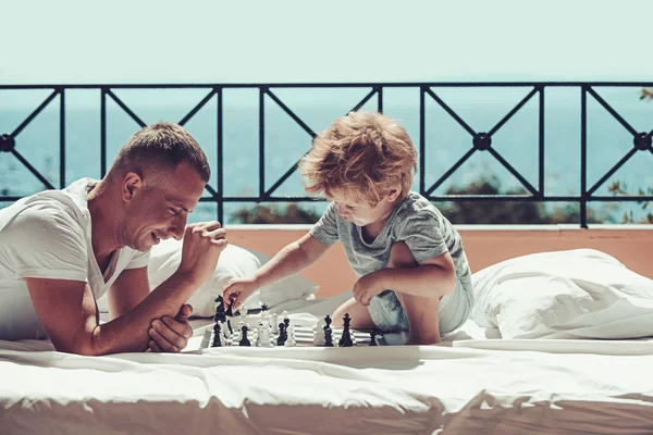 Dítě hrát šachy s otcem. Letní dovolená šťastné rodiny. Rodinné cestování s klukem na den otců. otec se synem na balkóně hrát šachy. Lásku a důvěru jako rodinné hodnoty — Stock fotografie