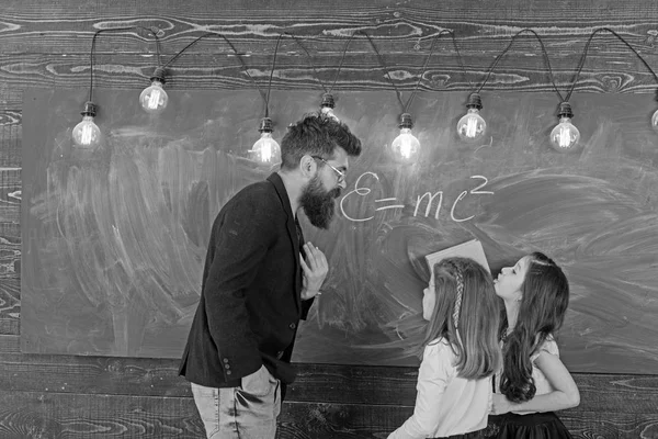 家教教儿童学生在课堂上。老师用粉笔在黑板上写字。小女孩在学校董事会里听留胡子的男人说话。老师和学生在课堂上上课。教育和学校 — 图库照片