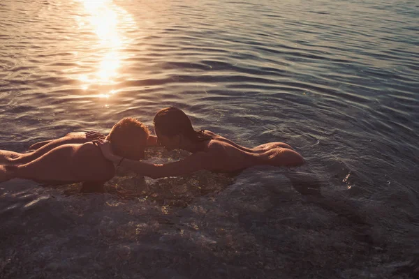 性感的女人和男人有性游戏。性感女人亲吻人在日落水海滩. — 图库照片