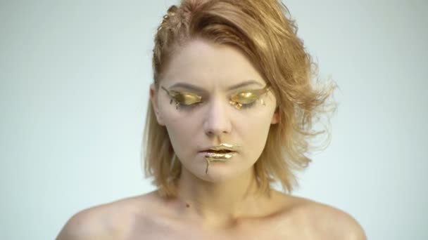 High Fashion modell kvinnan i gyllene utgör poserar i studio. Porträtt av vacker sexig tjej, trendiga glödande guld hud make-up. Konst design gör upp. Flicka med guld makeup. — Stockvideo