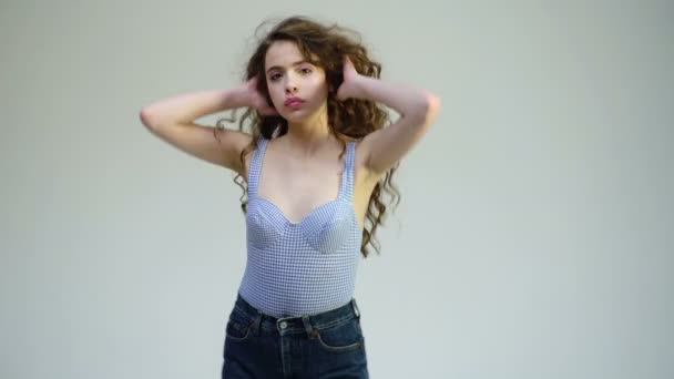 Sexy young woman is dancing isolated on white background. Parisian curly girl dancing. Girl is in a blue swimsuit and jeans. — Stock Video