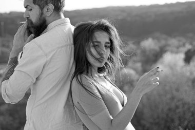 Açık havada, Sigara rahat yüzündeki defocused arka plan, doğa birkaç. Erkek ve kadın bahar gününde sigara tutar. Aşık çift harcamak zaman açık havada ve yasaktır. Sigara alışkanlığı kavramı.