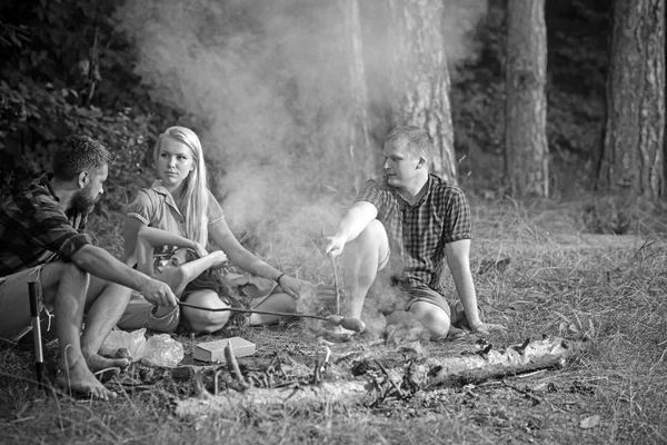 Ομάδα φίλων κατασκήνωση στο δάσος. Άνθρωποι που έχουν τη διασκέδαση μιλάμε γύρω από την πυρά προσκόπων. Ψήνοντας λουκάνικα πάνω στη φωτιά — Φωτογραφία Αρχείου
