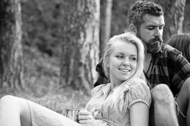 Sarışın kız erkek arkadaşı yaslanmış. Kamp ateşi yanında çimenlerin üzerinde oturan arkadaş grubu. Doğada romantik bir hafta sonu