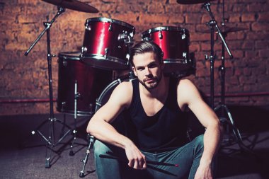 Beat sizinle olsun. Rock konser müzik kulübü provada. Yakışıklı adam vurmalı enstrüman aşamada oturamaz. Müzik aleti, adam davulcu. Enstrümantal müzik keyfi. Rock yıldızı ya da rock'çı